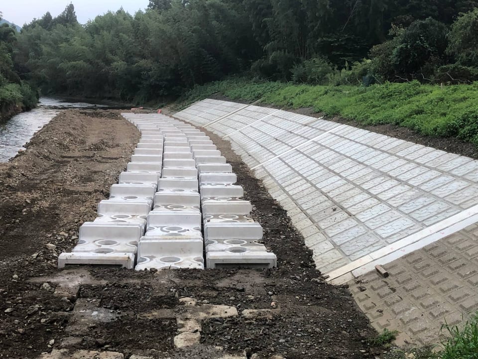 川沿いの護岸工事の現場。ブロック張りの法面と、並べて据え付けたコンクリートブロック